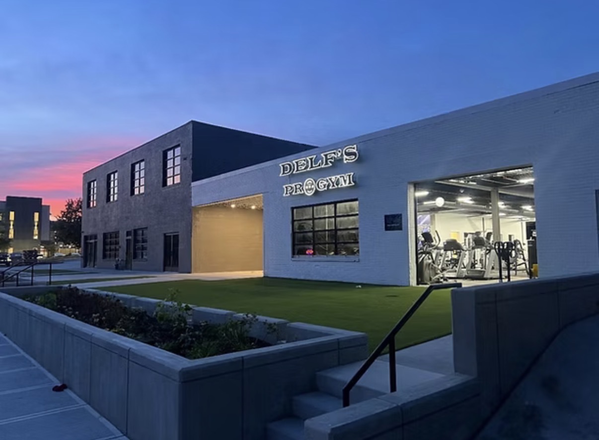 Delf's Pro Gym exterior at dusk with the lit sign above the entrance