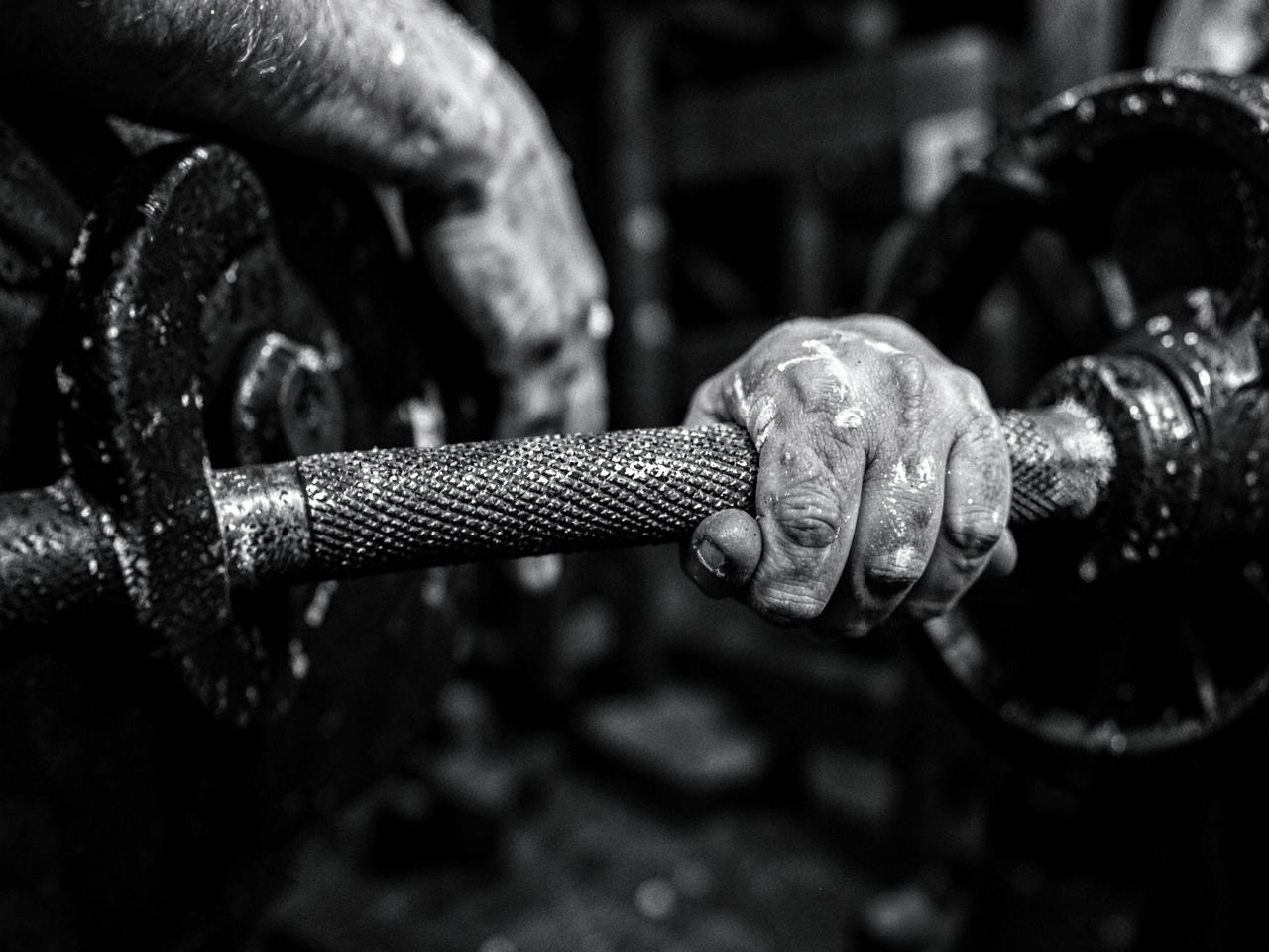 Chalked hands gripping a knurled steel barbell