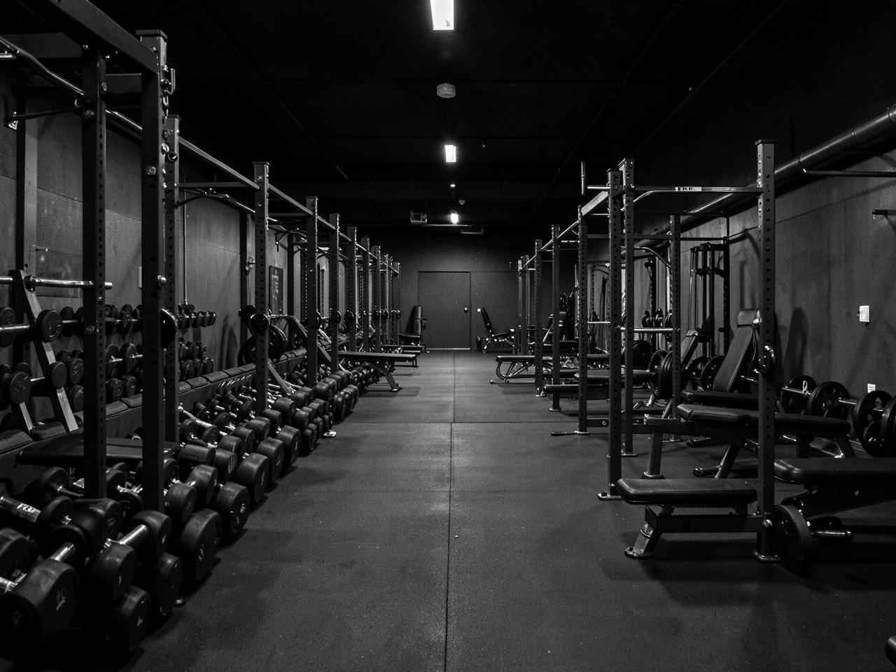 Rows of dumbbells and benches in a dark free-weight area